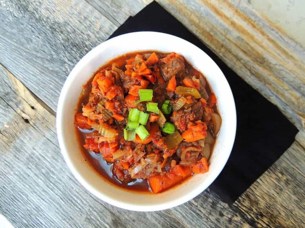 Buffalo Stew recipe finished and served in a white bowl with sliced green onion