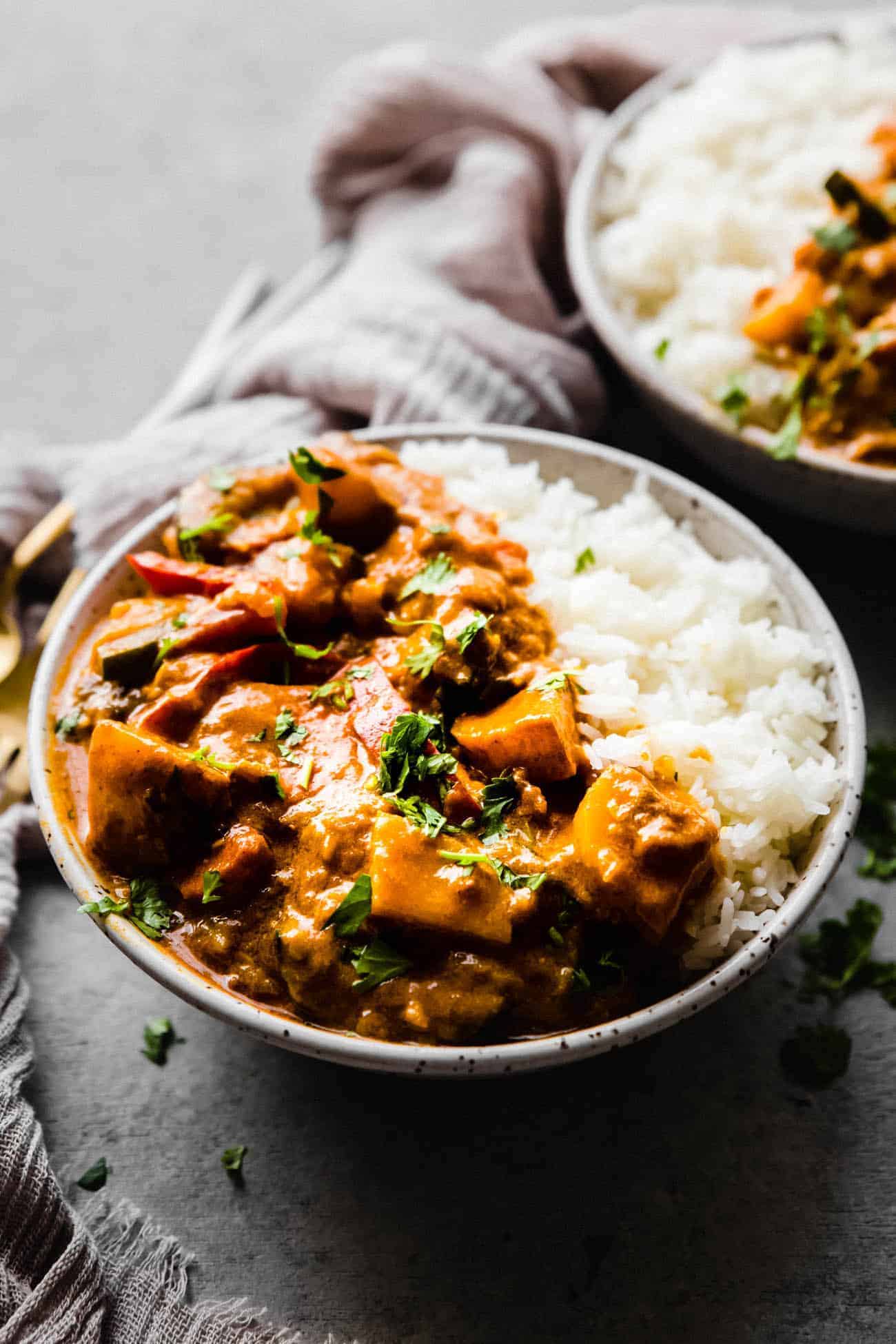 red curry in a bowl with white rice and cilantro on top